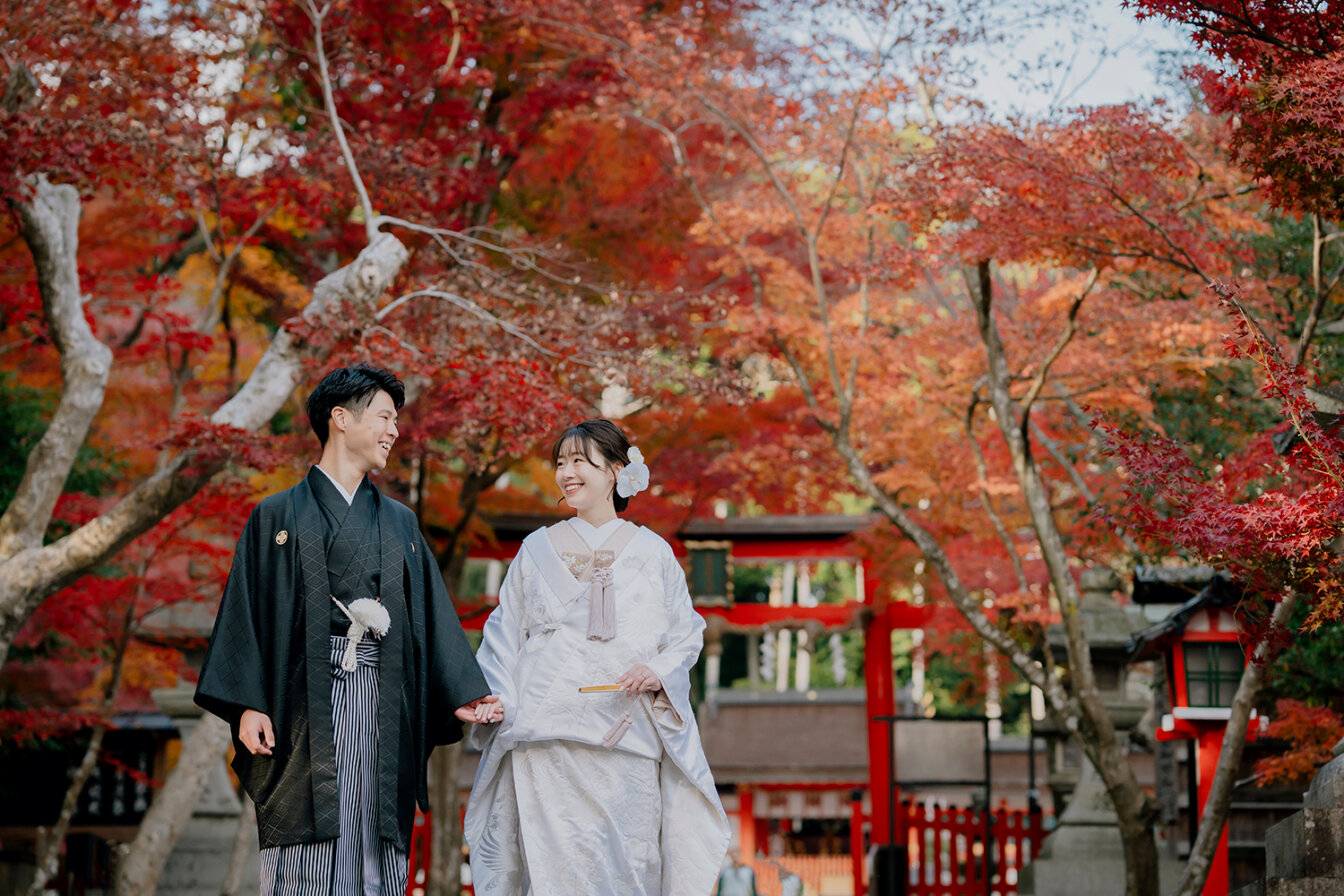 秋の大原野神社で参道を歩きながら和装前撮りを行う新郎新婦
