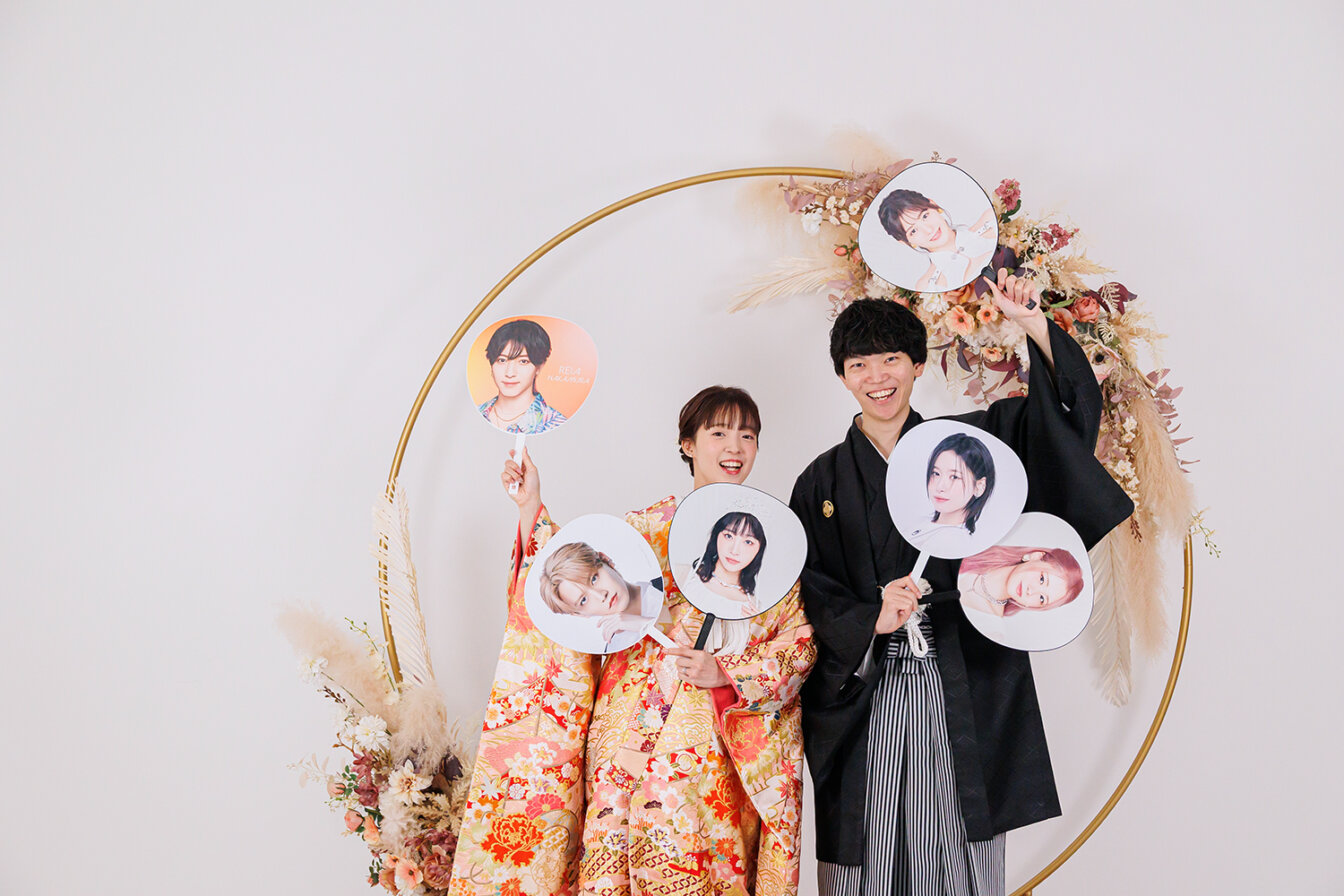 京weddingスタジオのフラワーアーチ背景で推しのうちわを持って和装前撮りを行う新郎新婦